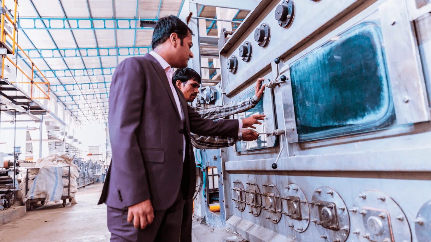 Business, India, Factory - Young Businessman with his factory floor supervisor inspecting the newly installed heavy machinery at a textile factory.